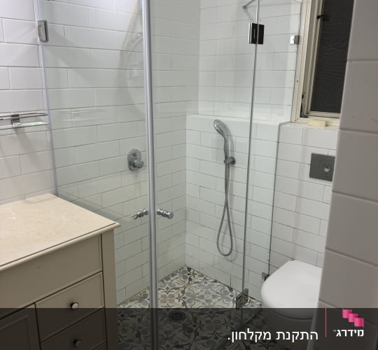 מקלחון זכוכית פינתי מותקן בחדר רחצה מעוצב